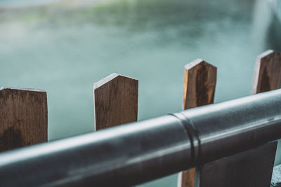 Close-up of wooden railing by water