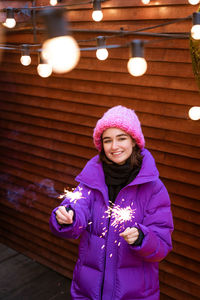 Caucasian girl is having fun in winter on street with sparklers in her hand