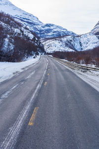 Road leading towards snowcapped mountains during winter