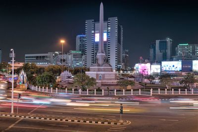 Light trails on city street by buildings at night