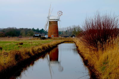 Landscape of windmill at norfolk broad at sunset with mill and grass reflected water norfolk uk
