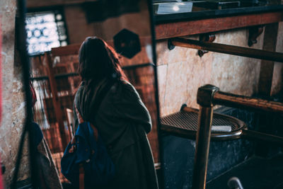 Side view of woman standing against wall