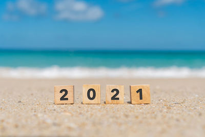 Text on sand at beach against sky