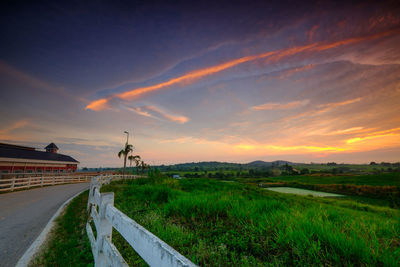 Road by land against sky during sunset