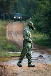 Side view of male army soldier in protective workwear walking against trucks