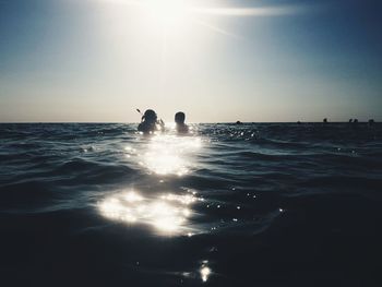 Silhouette people on sea against sky