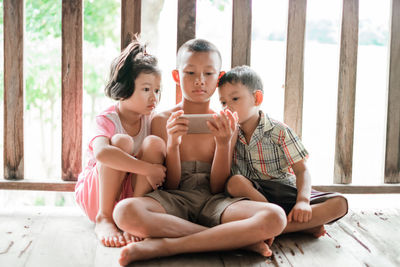 Siblings watching video over mobile phone while sitting on floor
