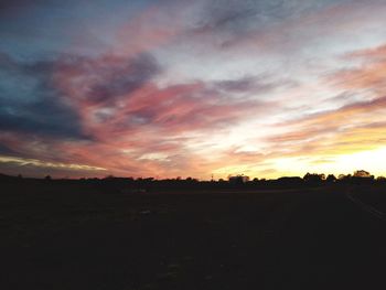 Scenic view of silhouette field against sky during sunset