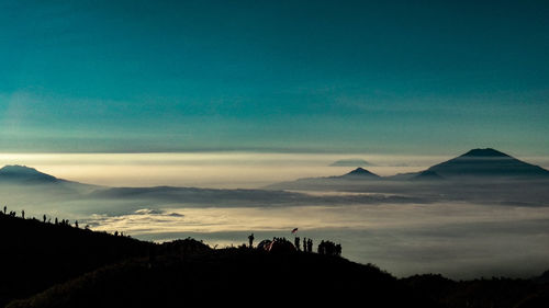 Silhouette people on mountain against sky during sunset