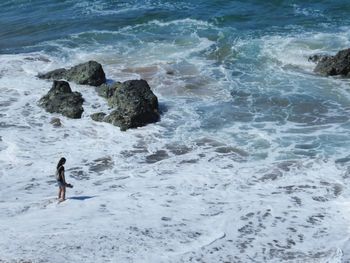 Rear view of people on rock in sea