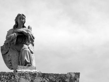 Low angle view of broken angel statue against sky