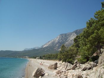 Scenic view of sea and mountains against clear blue sky