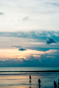 Silhouette people at beach against sky during sunset