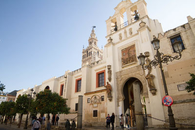 People on street amidst buildings in city against sky