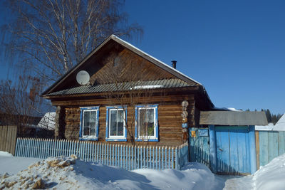 Built structure on snow covered landscape against clear blue sky