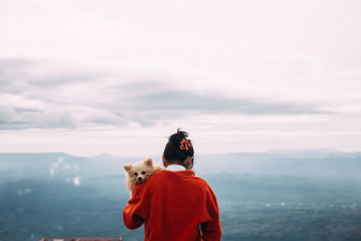 Rear view of woman with dog against sky