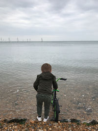 Rear view of man looking at sea against sky