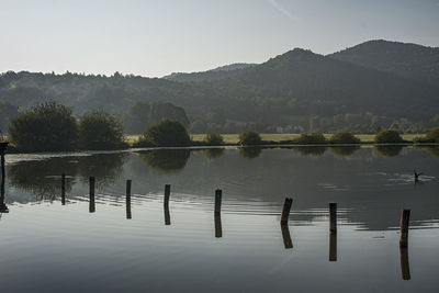 Wooden posts in lake against mountains