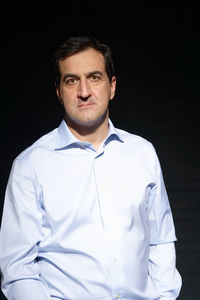 Portrait of young man standing against black background