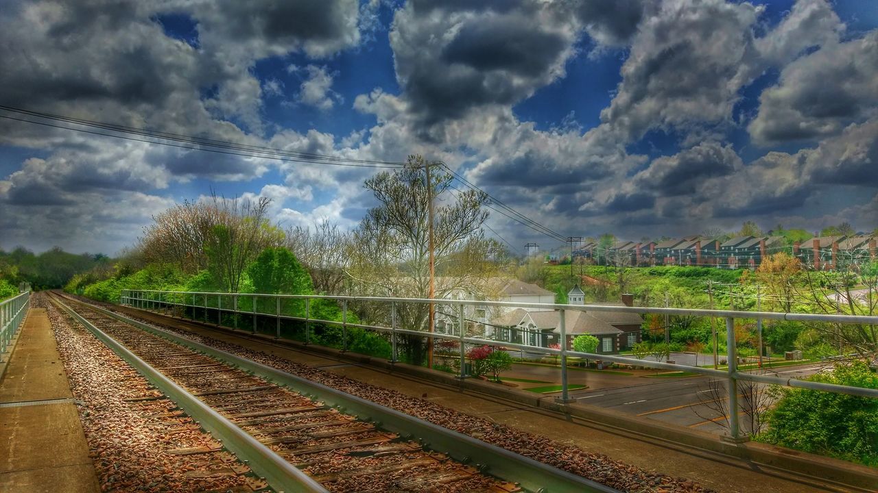 sky, cloud - sky, tree, cloudy, railroad track, cloud, rail transportation, built structure, architecture, transportation, nature, high angle view, day, growth, outdoors, no people, connection, blue, the way forward, railing