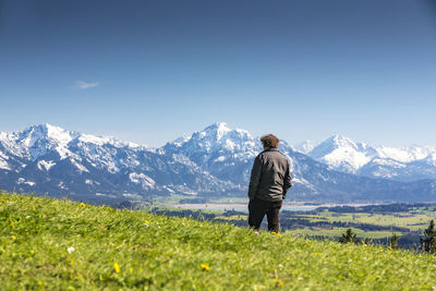 Rear view of man standing on mountain against clear sky