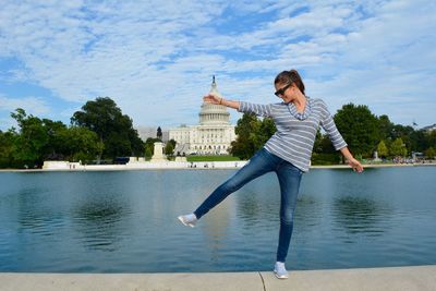 Full length of woman dancing against lake and sky