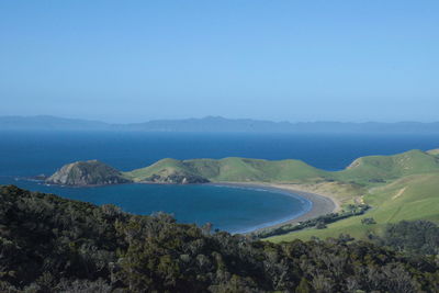 Scenic view of sea and mountains against clear blue sky