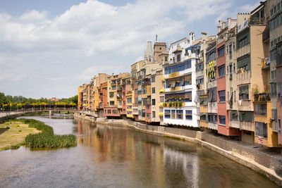 Buildings by river against sky in city