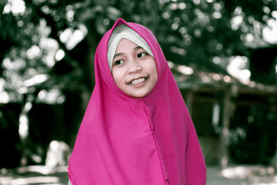 Smiling girl wearing hijab looking away outdoors