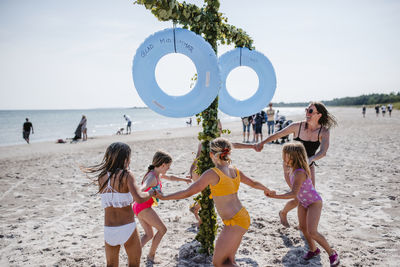 Mother with daughters dancing around maypole on beach