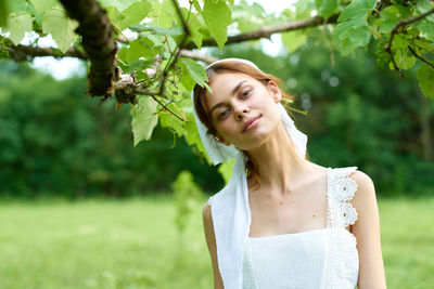 Young woman standing against plants