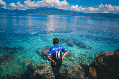 Rear view of man swimming in sea against sky