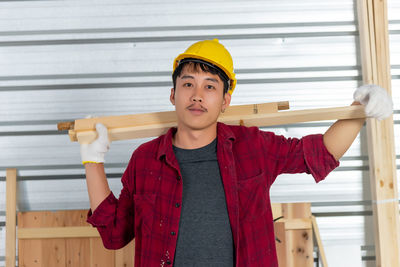 Portrait of young woman standing against wall