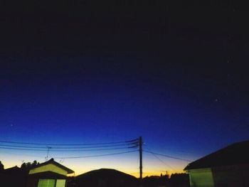 Low angle view of silhouette buildings against clear blue sky