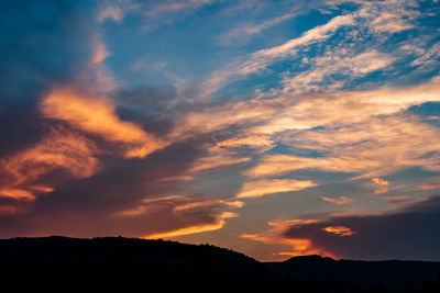 Low angle view of silhouette mountain against dramatic sky