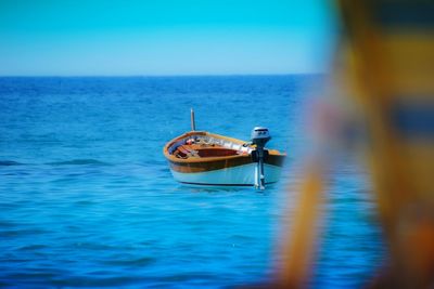 Boat moored on sea against clear sky