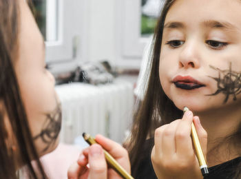 Portrait of a caucasian brunette girl applying make-up in the reflection of a mirror.