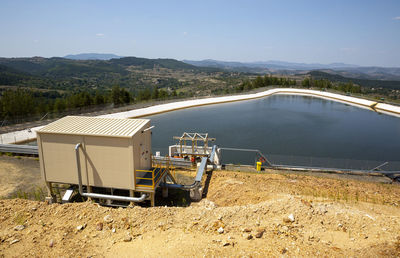 Construction site by lake against sky