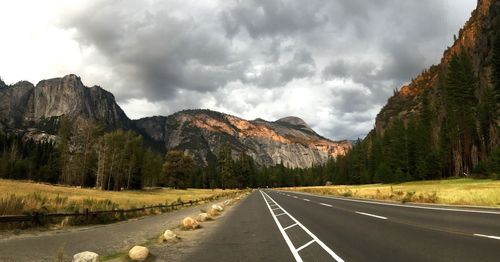 Road by mountains against sky