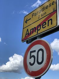 Low angle view of road sign against sky