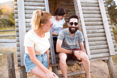 People sitting on log cabin outdoors