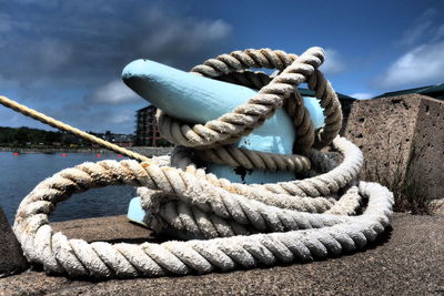 Close-up of rope tied to bollard against sky
