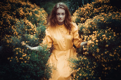 Portrait of young woman standing against plants