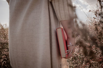 Close-up of woman holding a book on field 