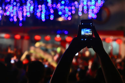 Close-up of hand photographing on mobile phone at nightclub