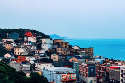 Houses by sea against clear blue sky