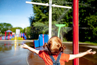 Behind iew of young girl playing at a splashpad