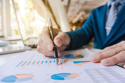 Midsection of businessman planning over graph at desk