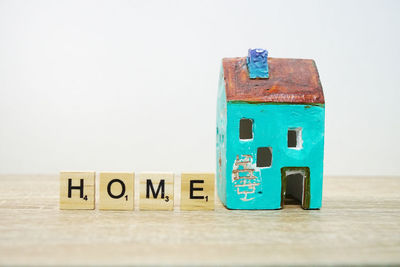 Close-up of model home with text on wooden blocks against white background