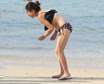 Full length of young woman standing at beach